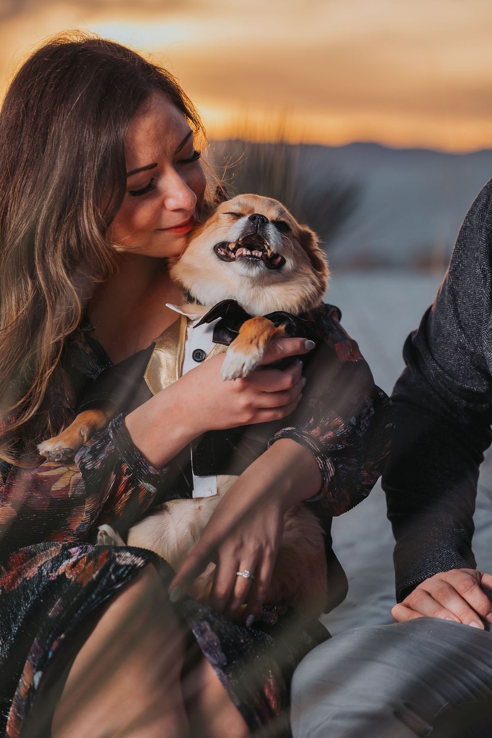 A couple shares tender moments with their dog during a sunset photoshoot at the beach.