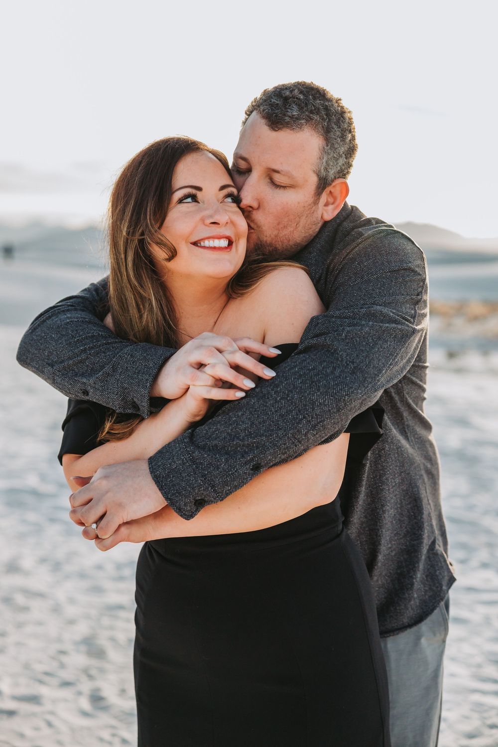 Romantic couple embracing and sharing tender moments on a beach at sunset, captured in a series of intimate photos.