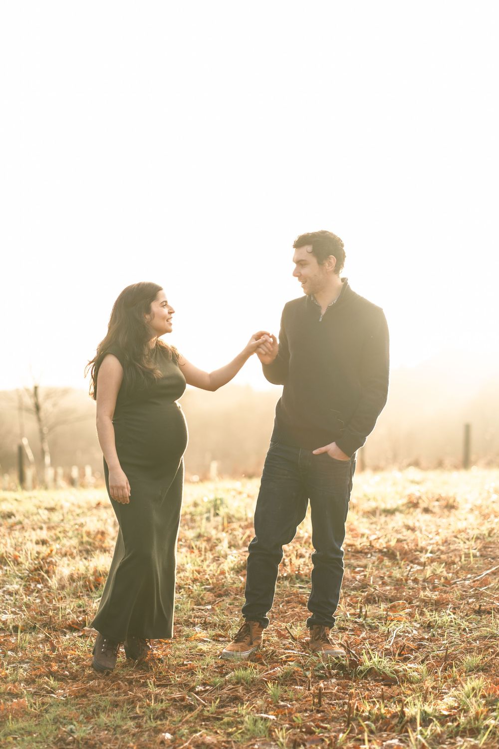 A couple shares a romantic moment in a sunlit autumn field during a marriage proposal.