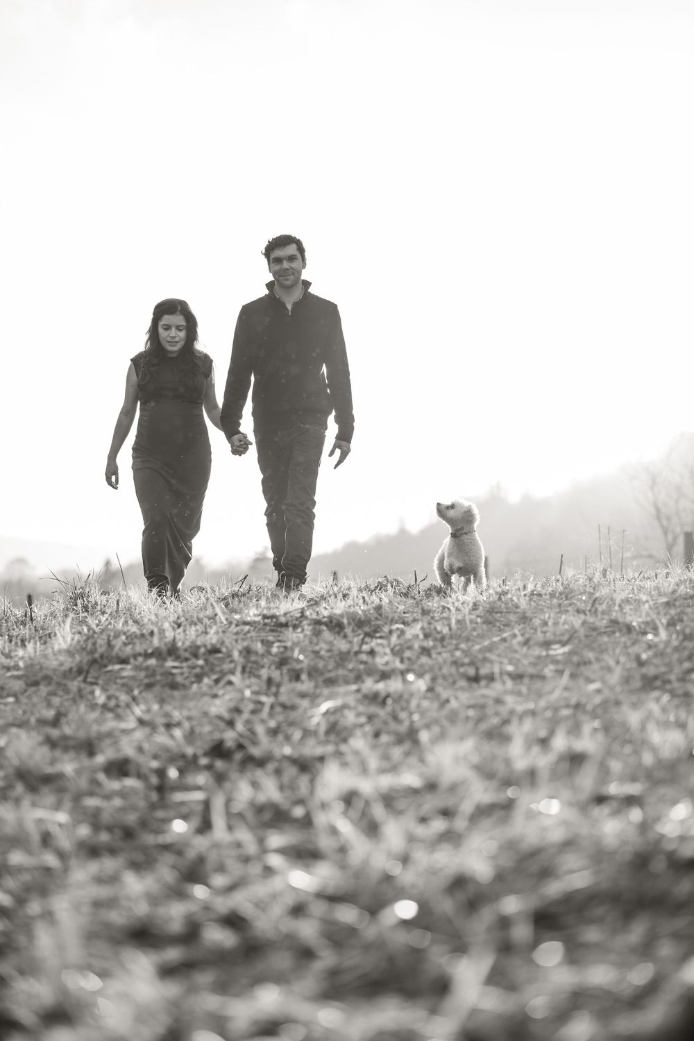 People walking together through a misty field in black and white, captured from a low angle perspective.