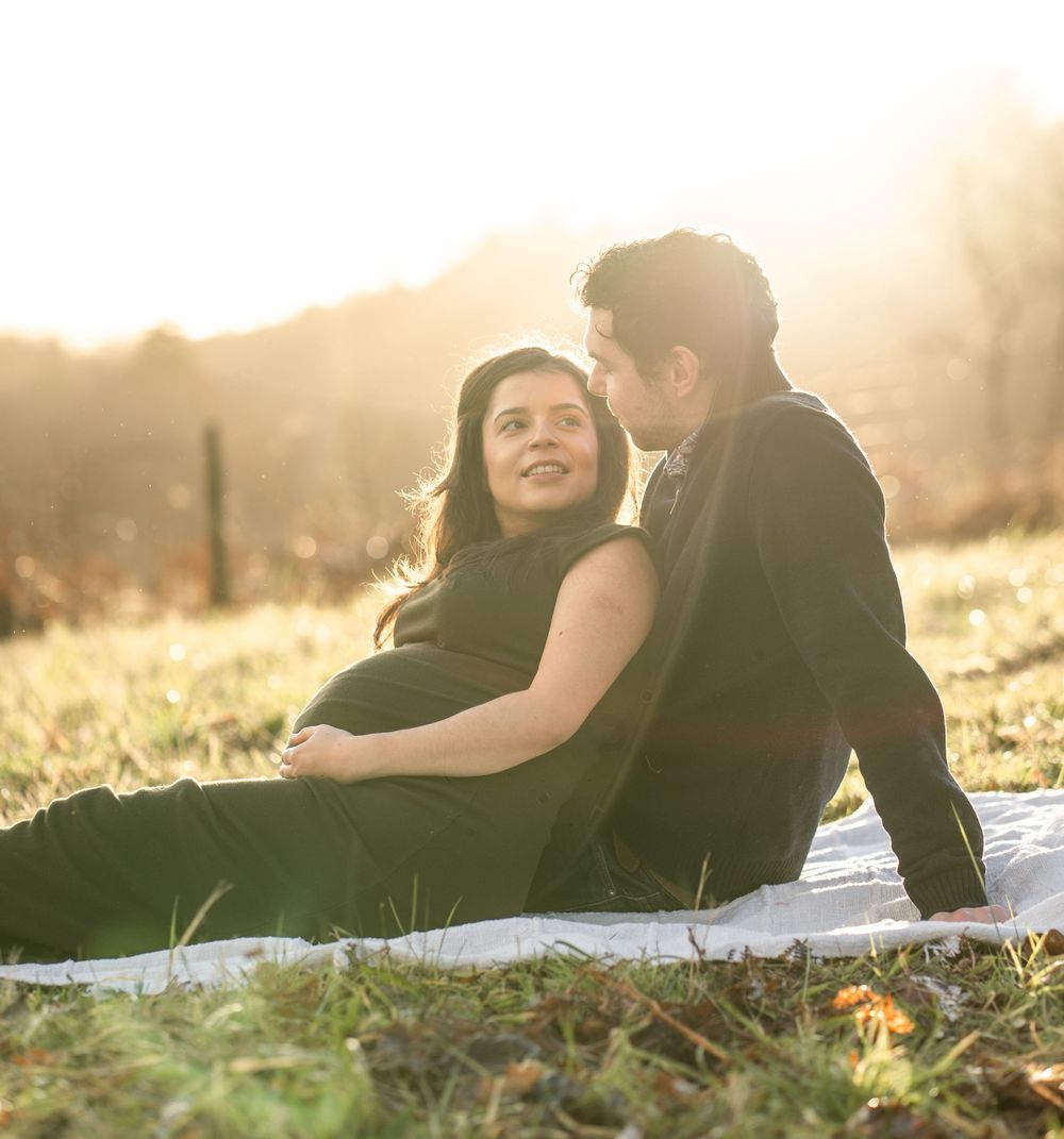 Couple relaxes on a blanket in a sun-drenched field during their photoshoot.
