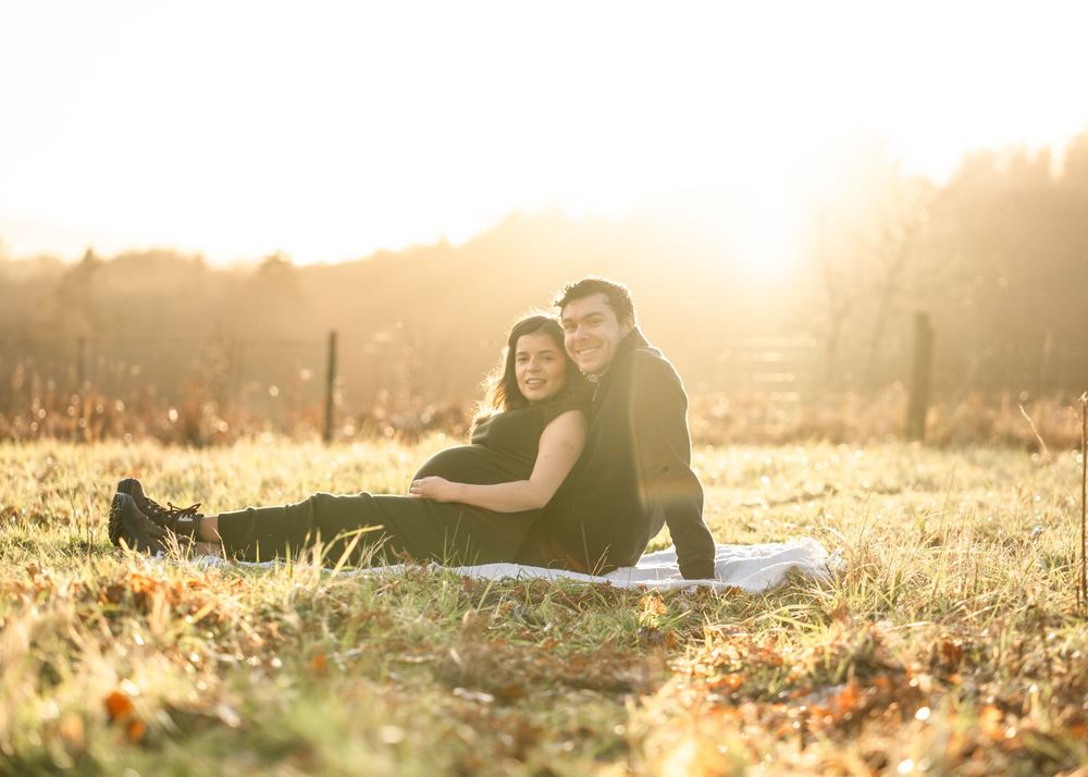 Panoramic view of couple lying in grass during golden hour photoshoot.