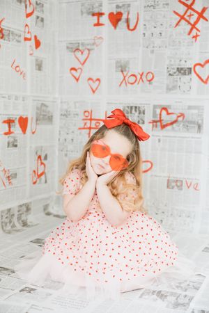 A series of photos showing a couple kissing against a white wall covered in red heart doodles and graffiti.
