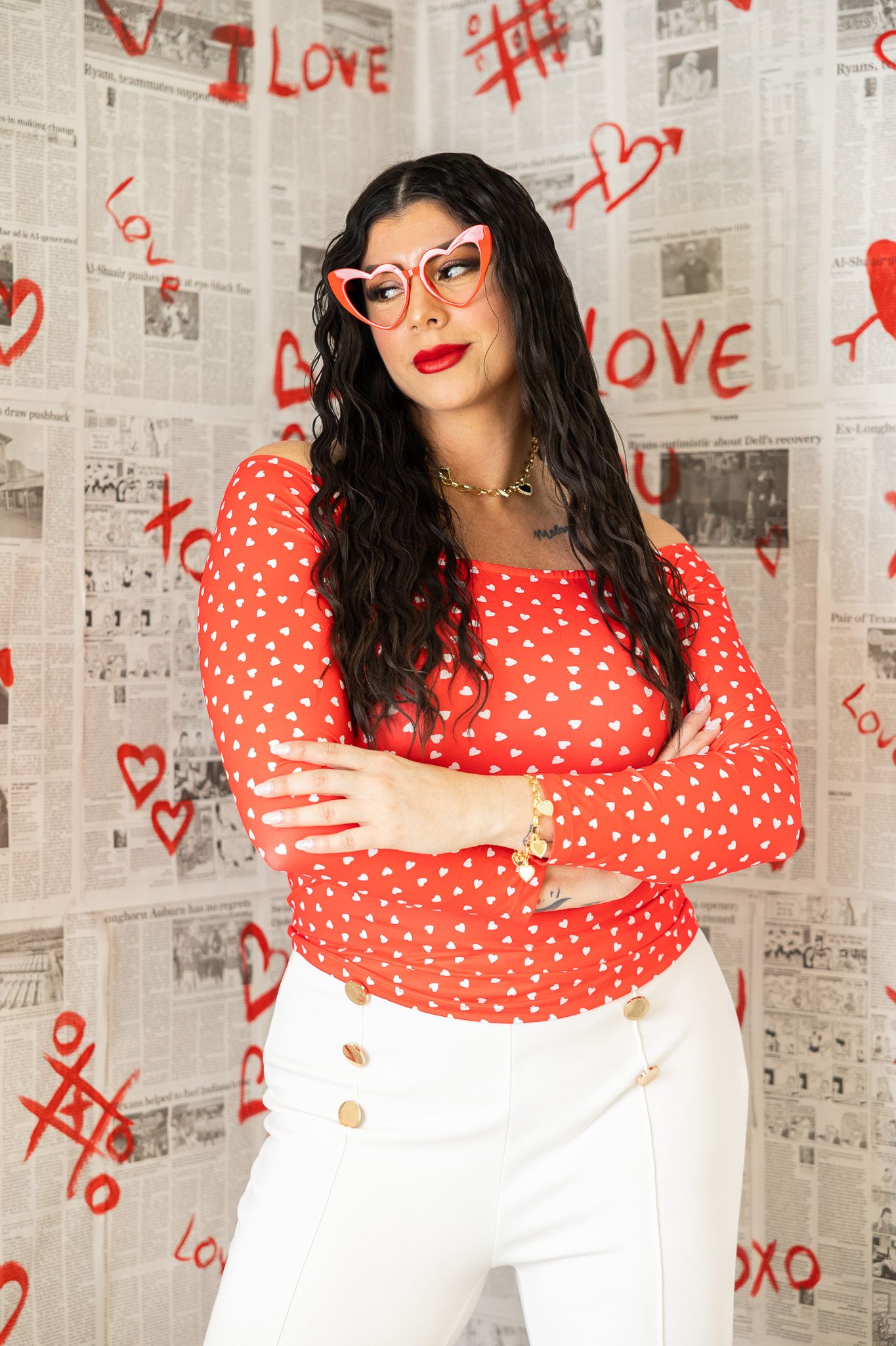 A polka dot red dress against a newspaper wall background with hand-drawn red hearts and love graffiti decorations.