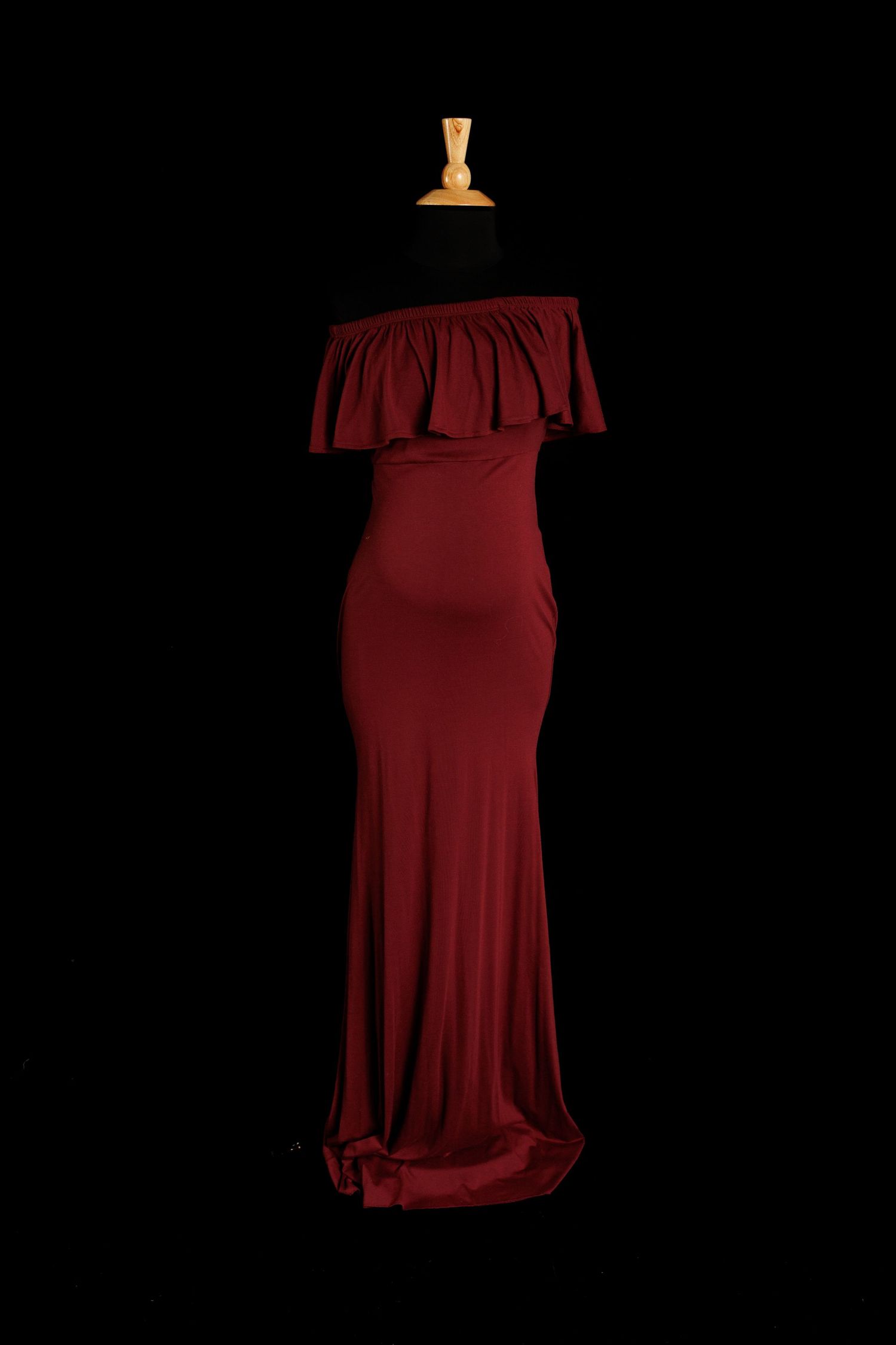 Burgundy off-the-shoulder maternity gown with ruffled neckline and fitted floor-length skirt