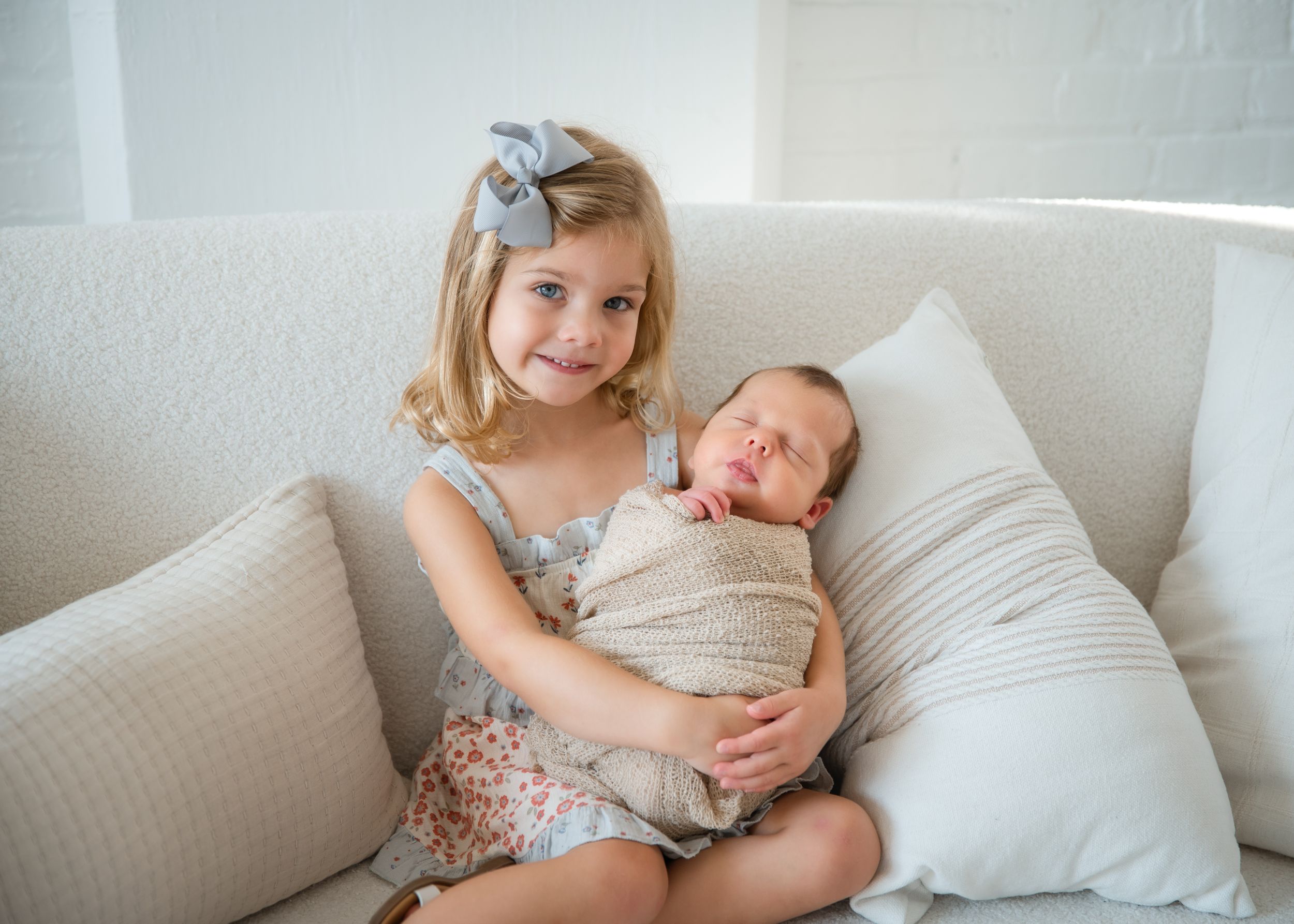 A series of tender moments between a parent and child relaxing together on a white couch in natural lighting.