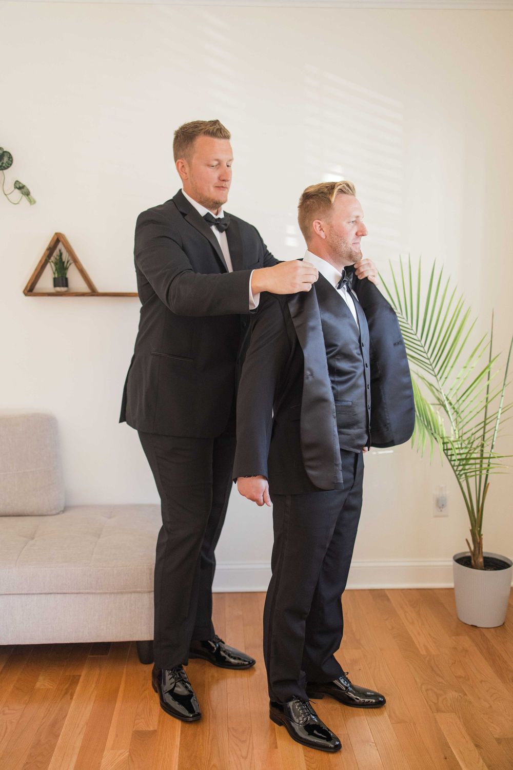 Evan's best man helps him put on his suit jacket prior to his wedding at a private home in Point Pleasant
