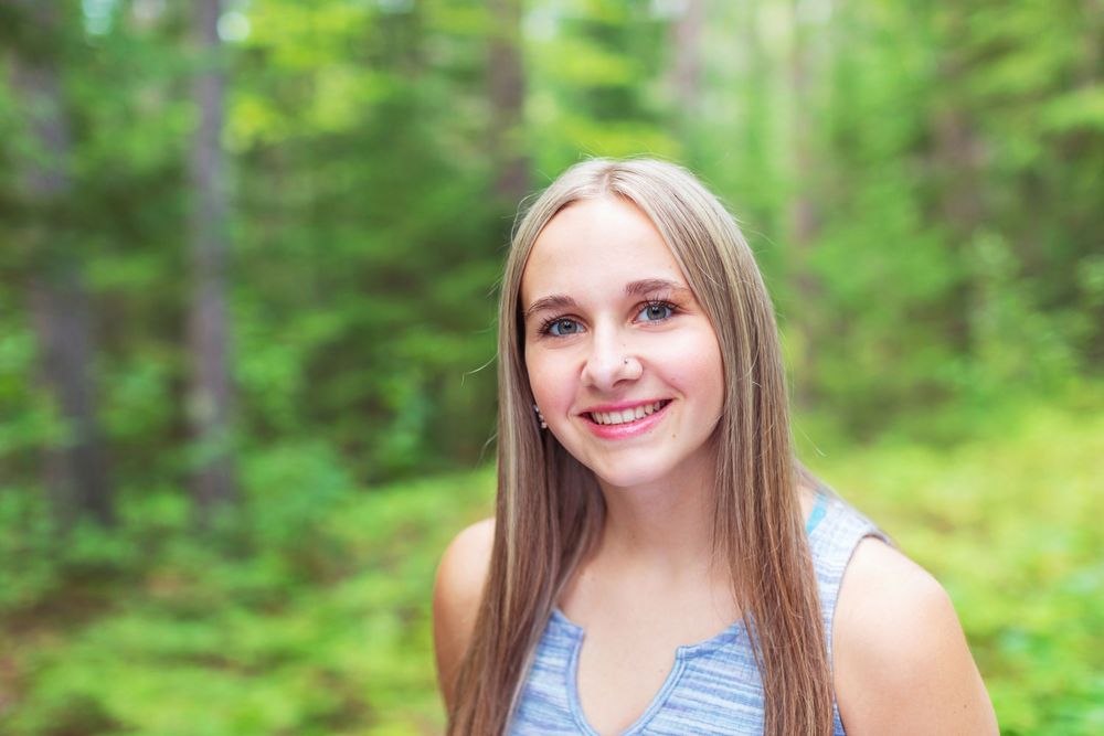 A series of similar photos showing someone in a blue top posing outdoors with a green forest background.