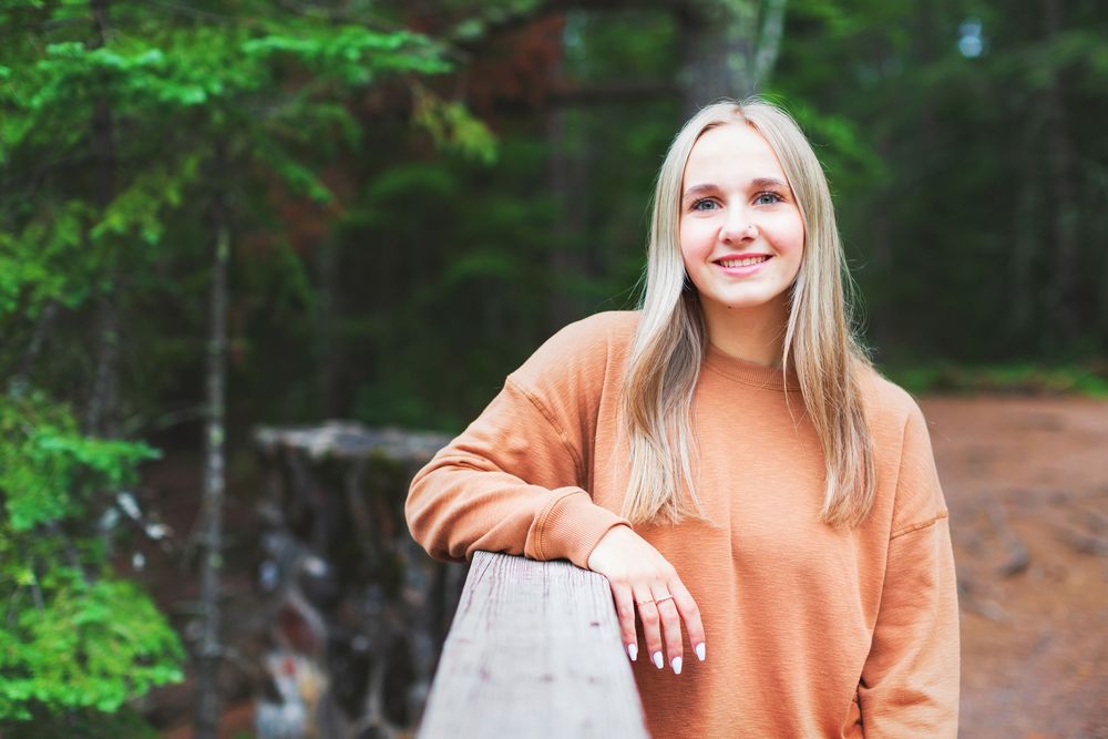 A casual outdoor portrait session in a lush green forest setting with natural lighting.
