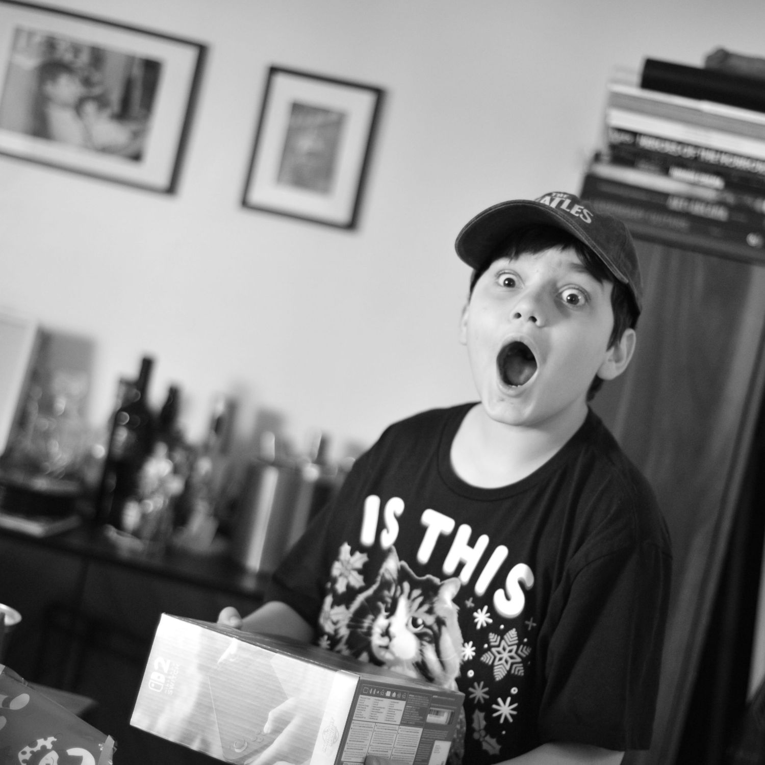 A black and white panoramic shot shows someone floating in dark rippling water while wearing a baseball cap.