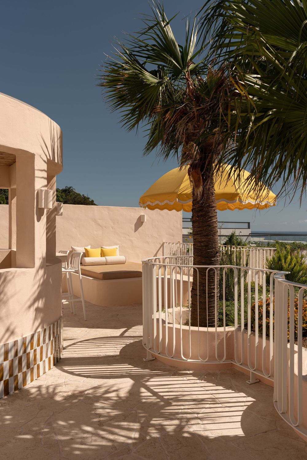 Curved white staircase with railings and palm trees against blue sky creates modern Mediterranean architectural aesthetic.