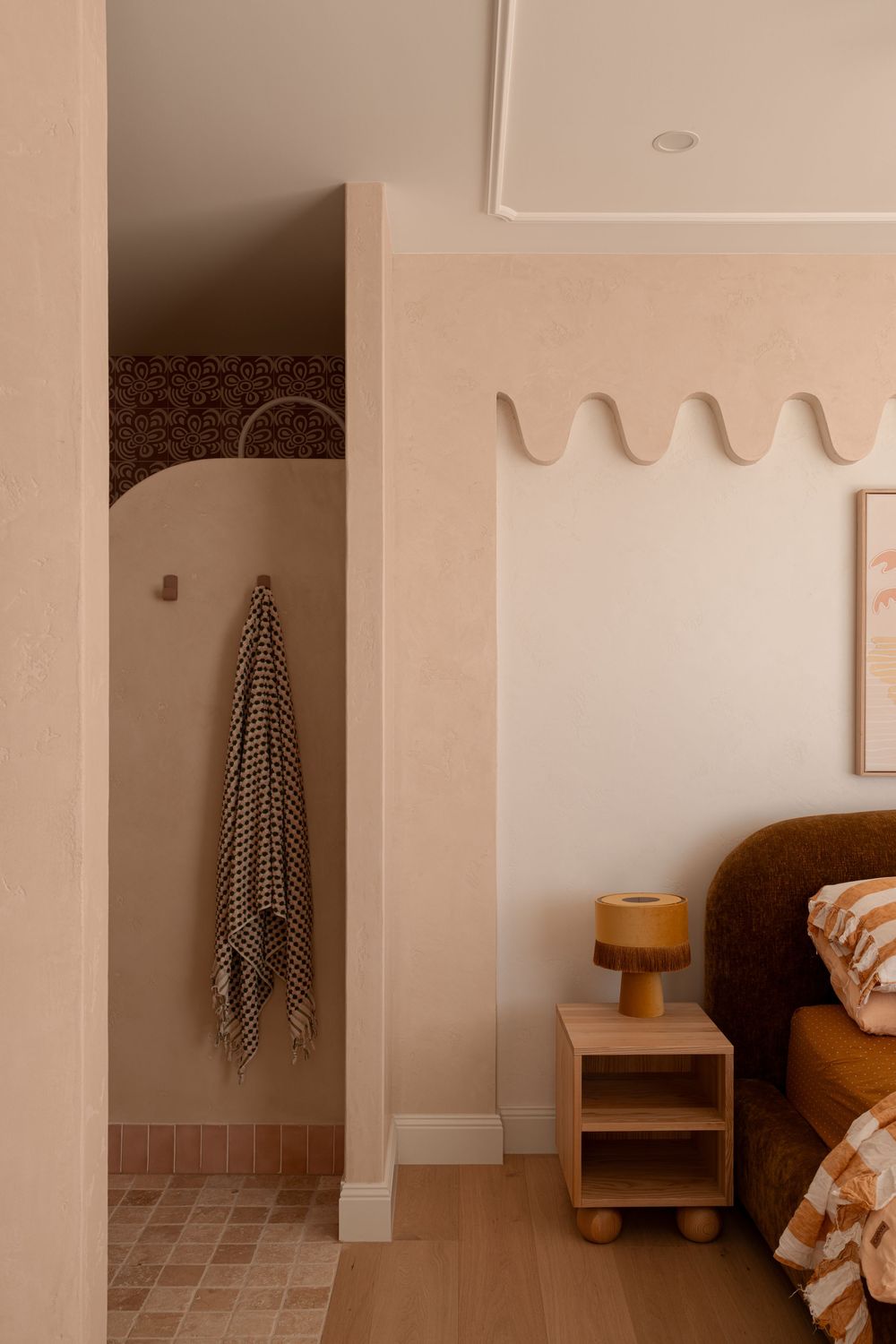 Minimalist white bathroom interior with wooden stool and striped towel hanging on wall hooks.