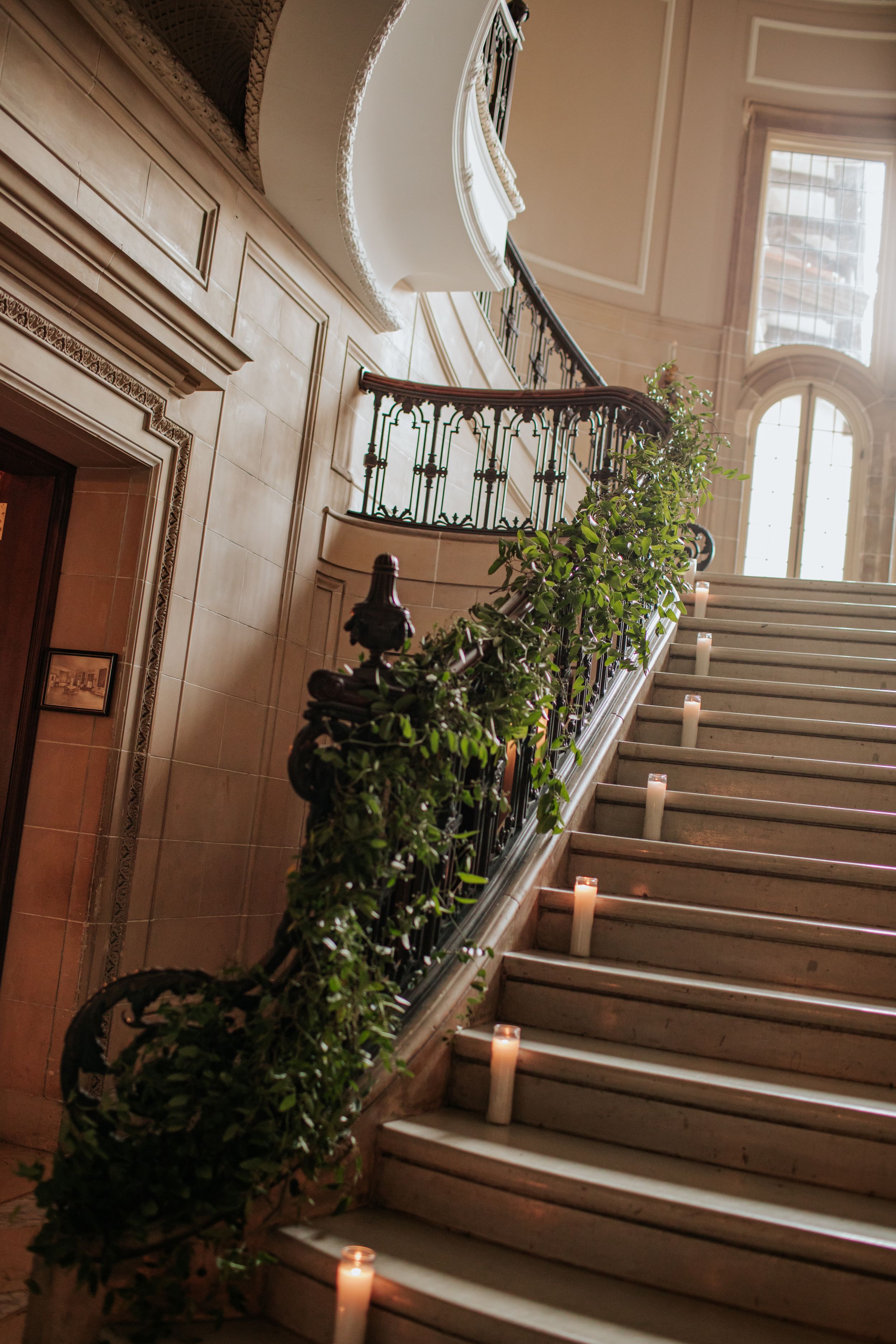 Elegant staircase with white walls and lit candles creating a romantic ambiance in an interior hallway.