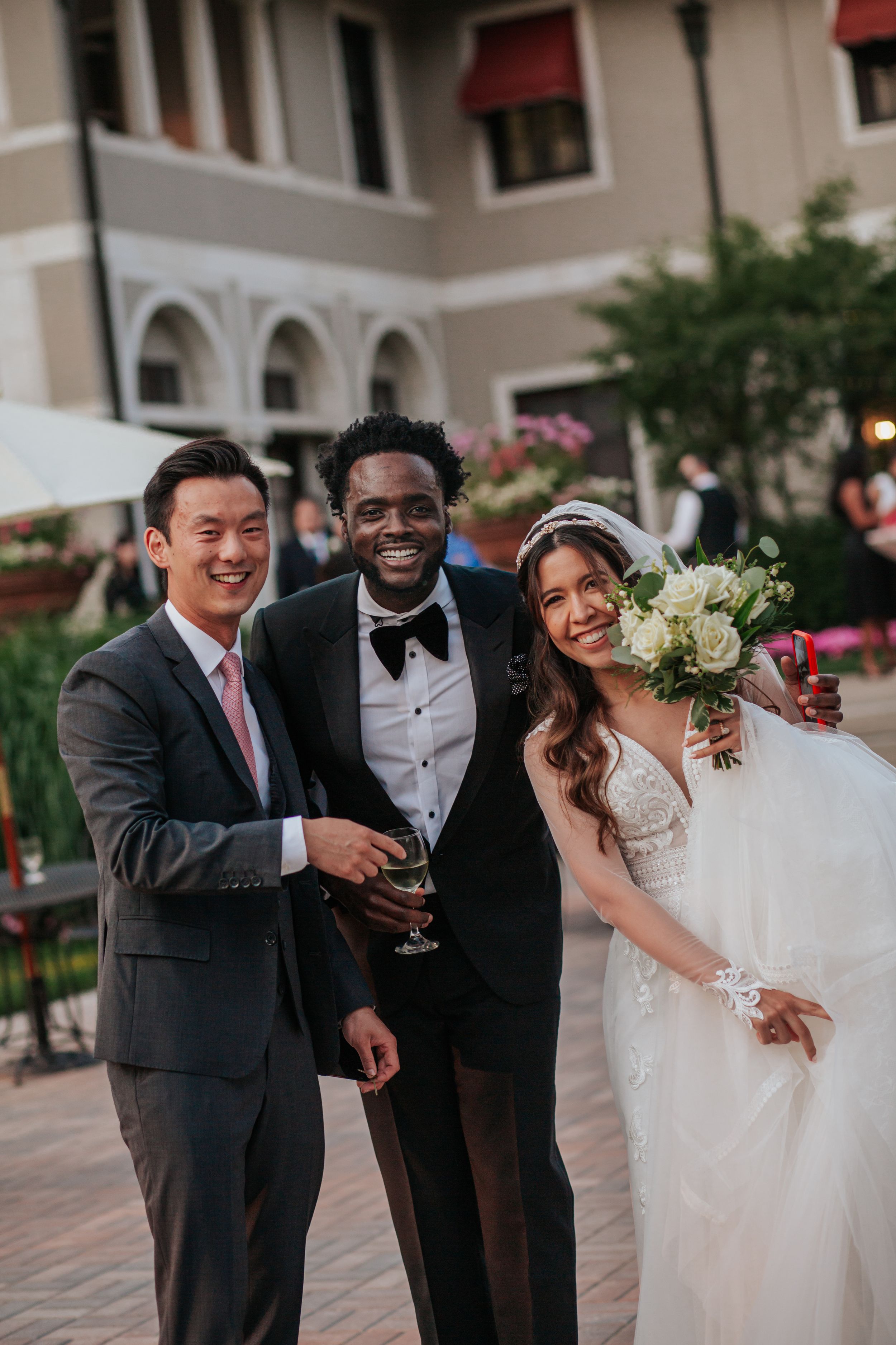 Wedding party members share joyful laughter and embraces during outdoor celebration at sunset.