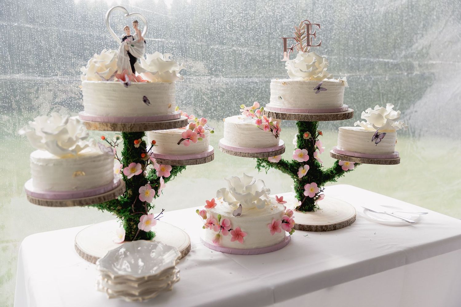 Elegant wedding cake display featuring multiple tiered white cakes adorned with floral decorations and cake toppers.