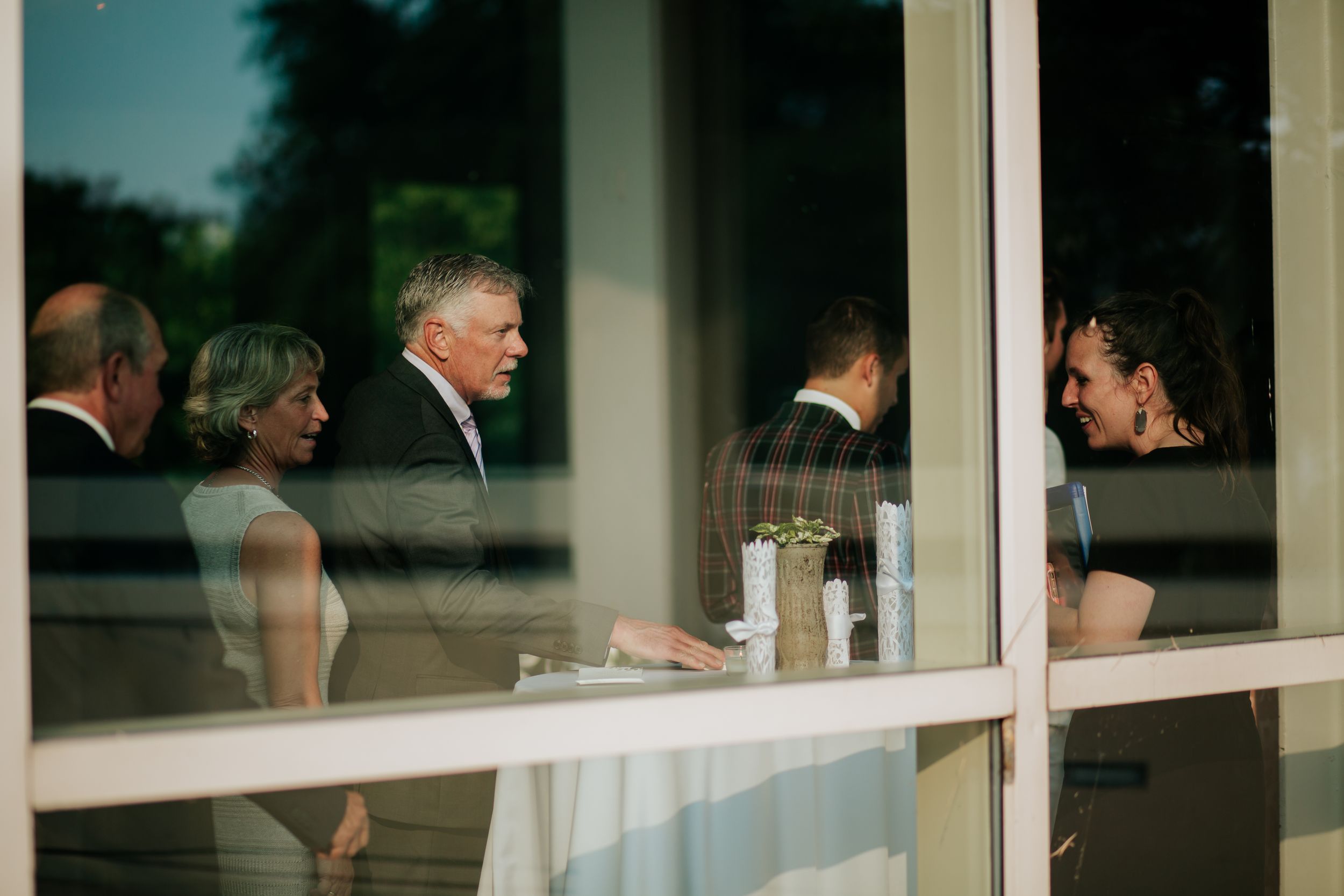 People having a conversation through a glass window at a restaurant or cafe.