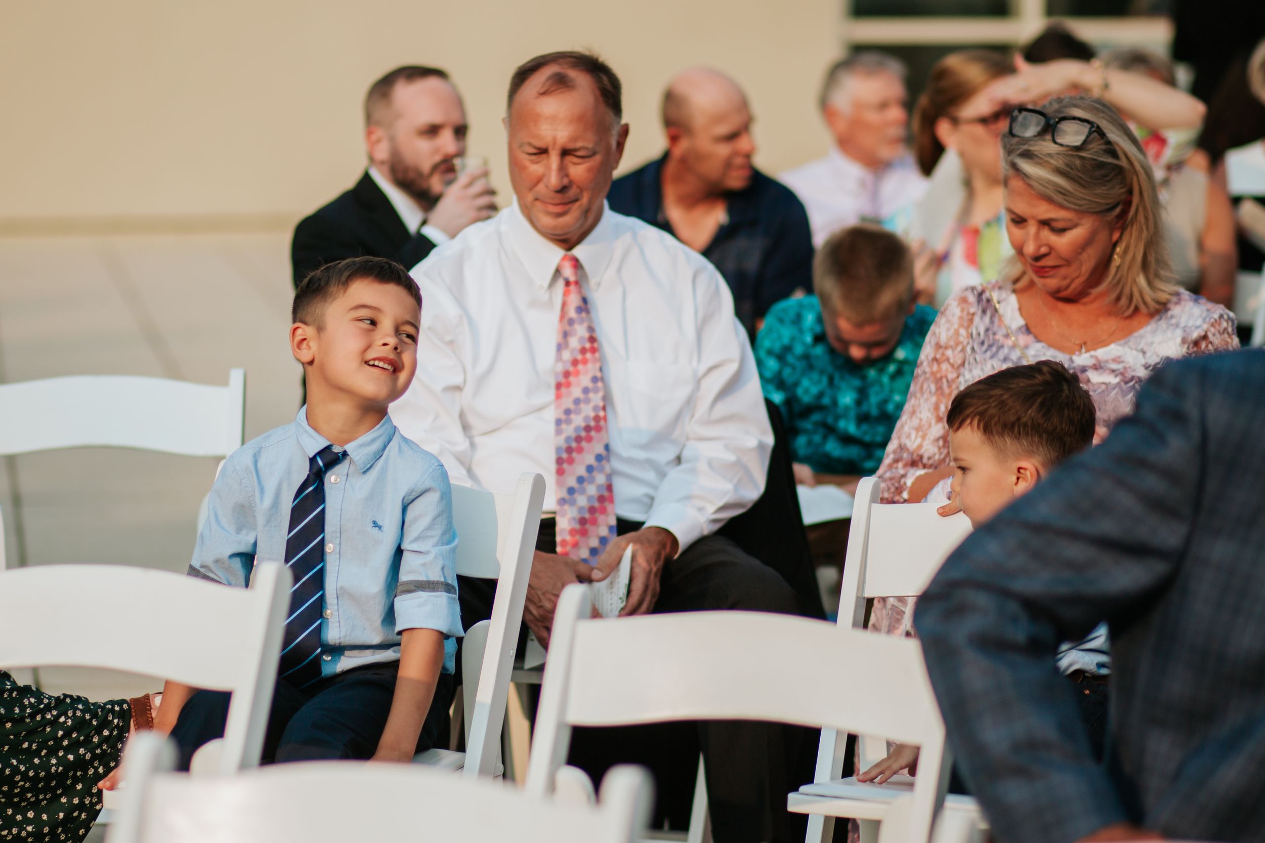 Wedding guests share candid reactions and laughter during a reception celebration at an indoor venue.