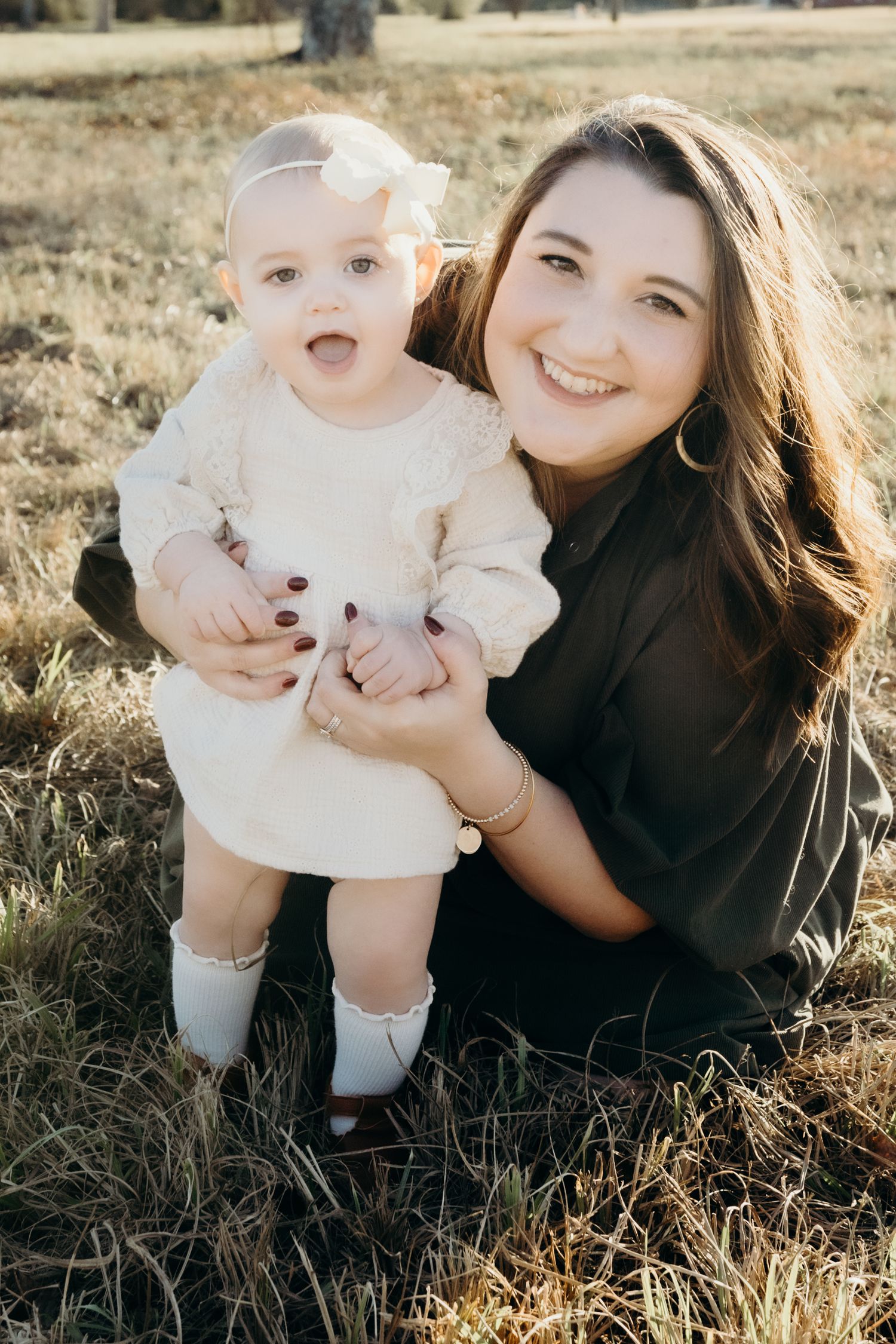 Mother and baby sharing joyful moment together in sunlit field.