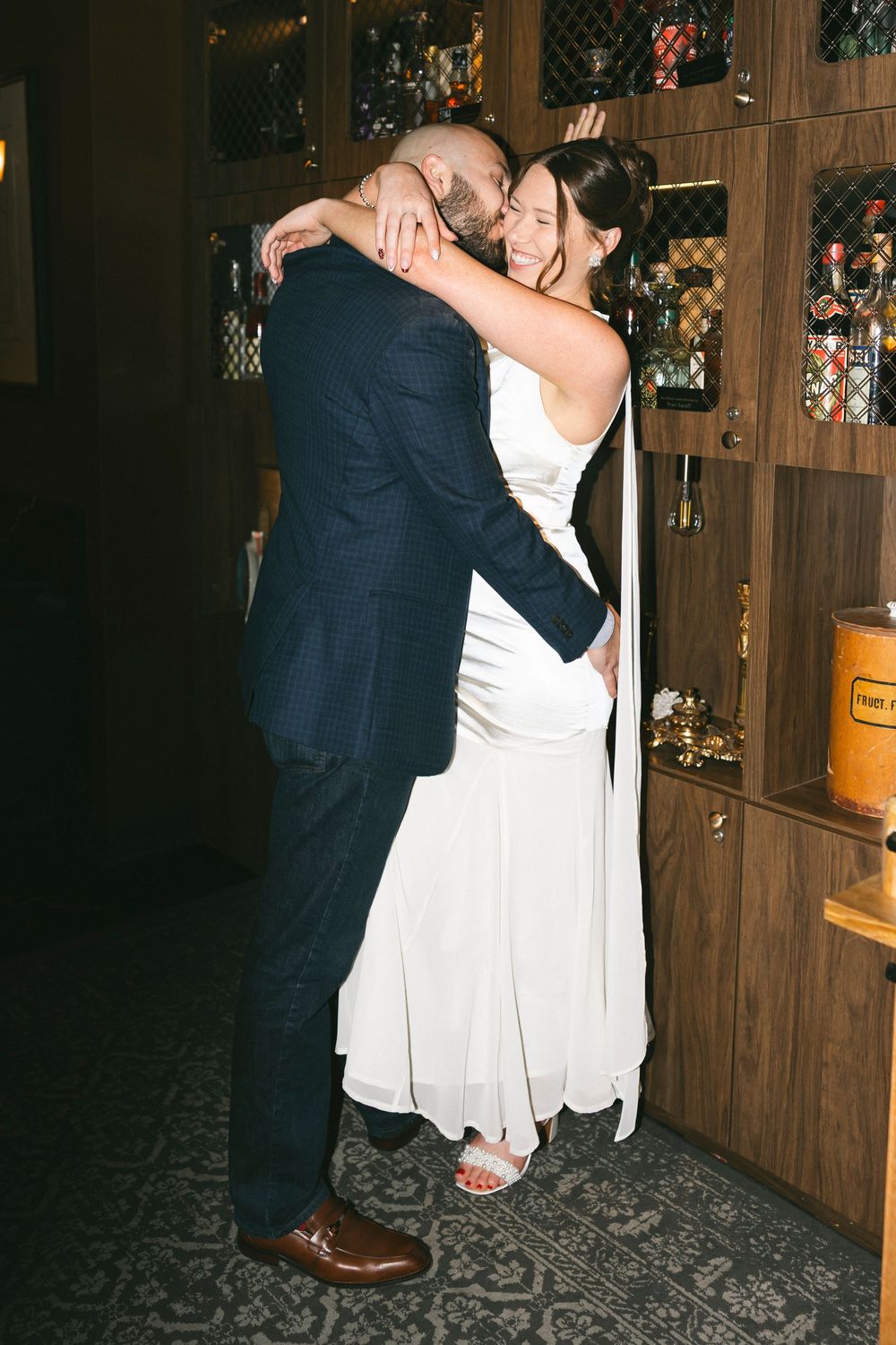 Dancing couples in formal attire move across a dark wooden floor in a bar setting.