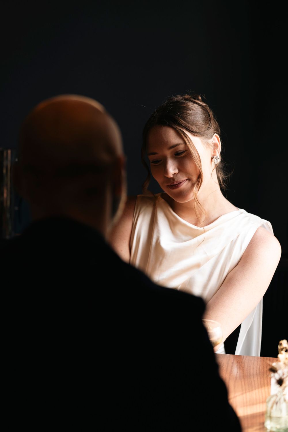 Dramatic side lighting creates a soft glow on white fabric against a dark background.