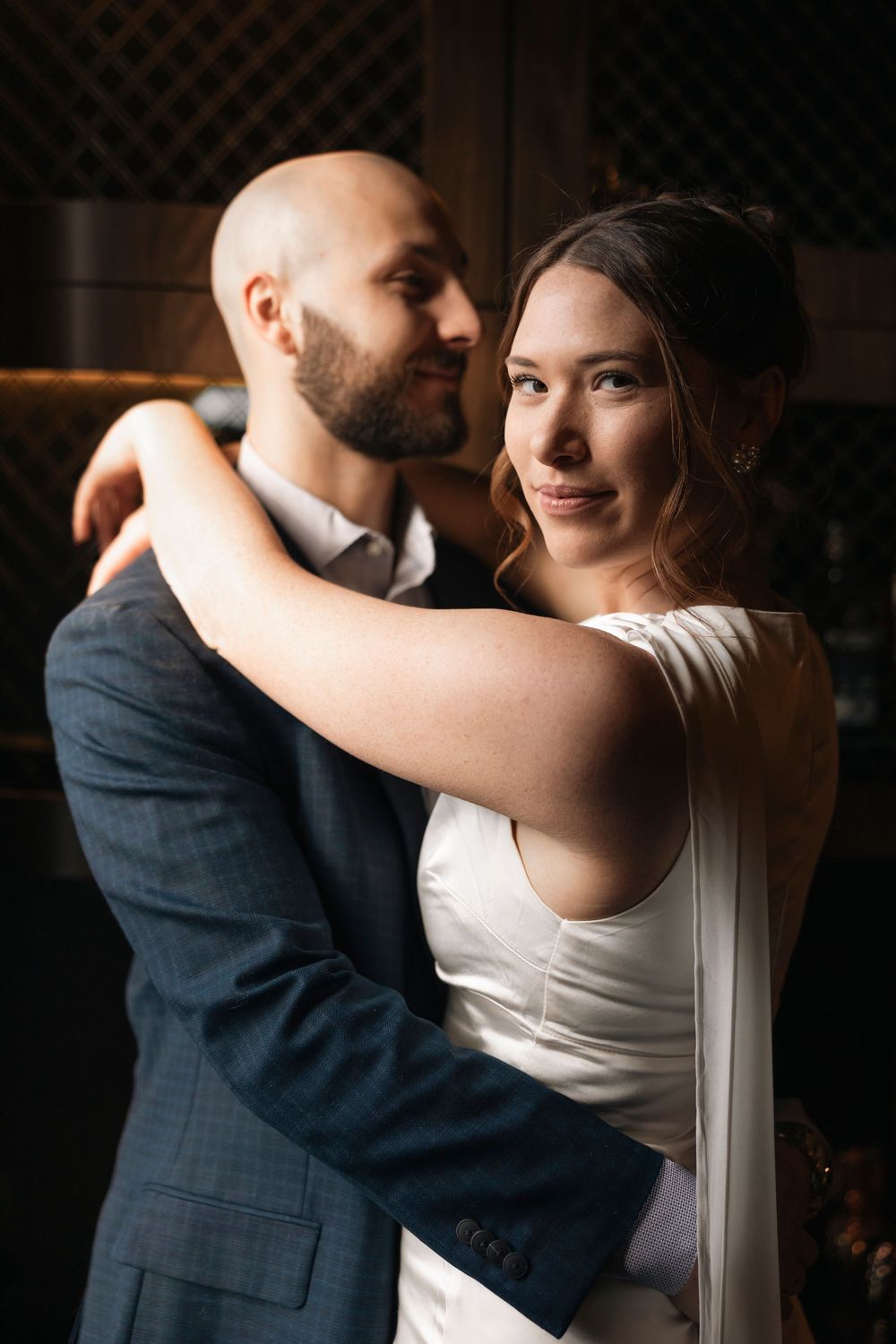 Intimate dance captured in dramatic window lighting against a dark background.