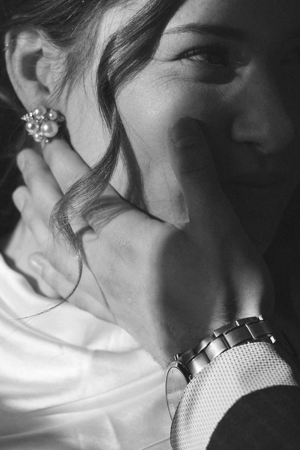 Close-up detail of jewelry and formal attire in black and white.