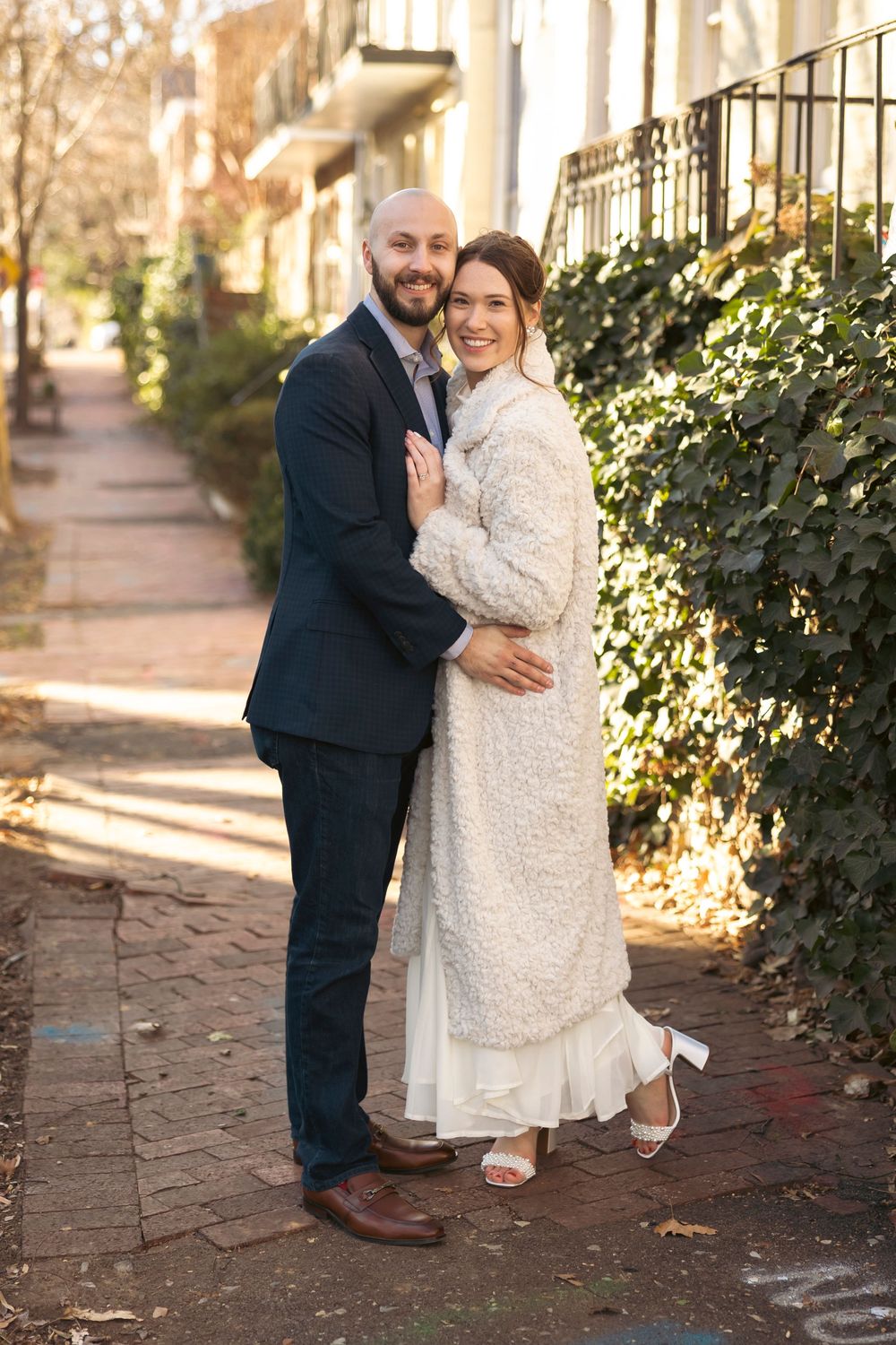 Couple sharing tender moments on a brick pathway lined with winter foliage.