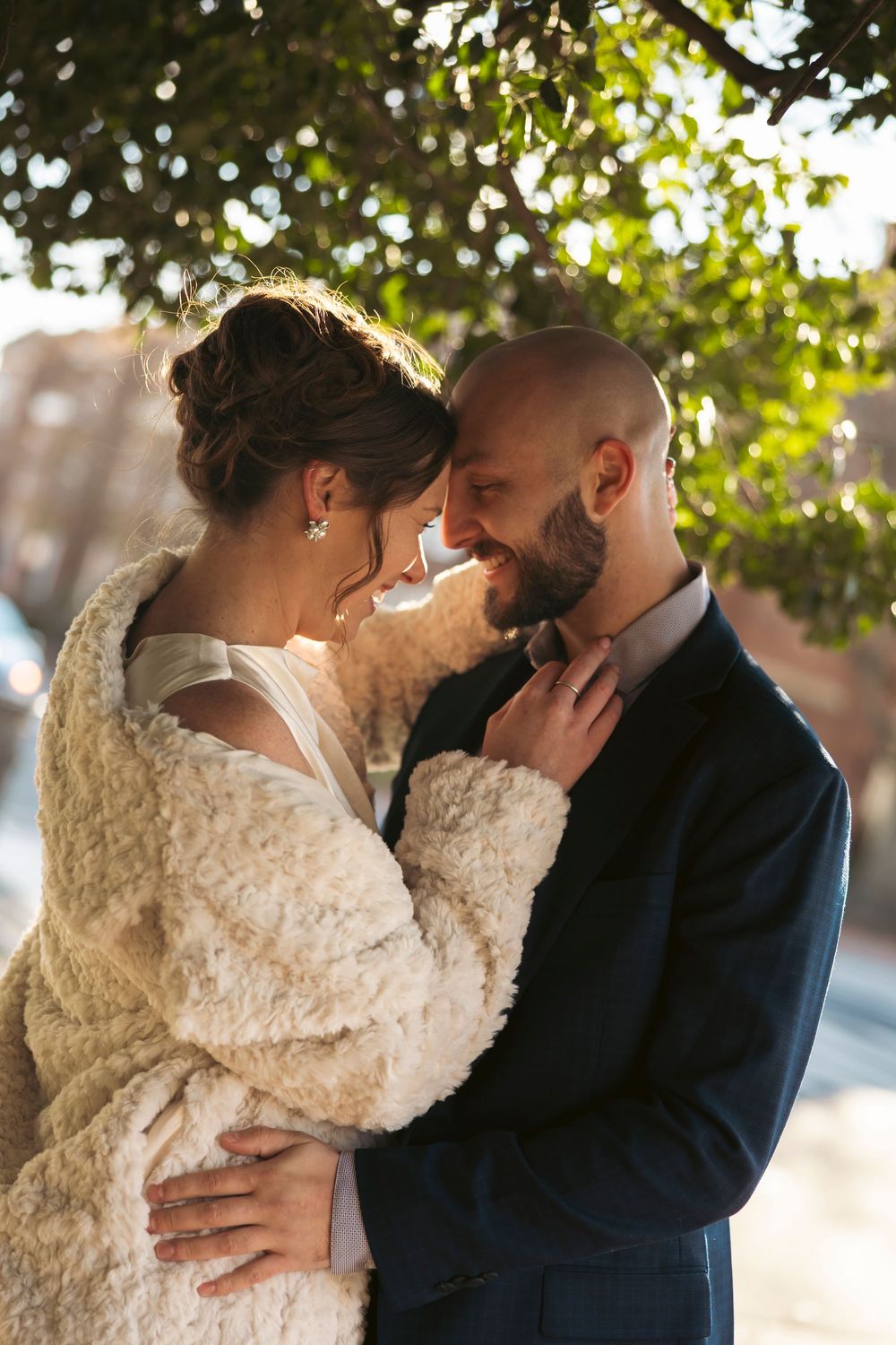 A couple in wedding attire sharing an intimate moment in golden sunlight.
