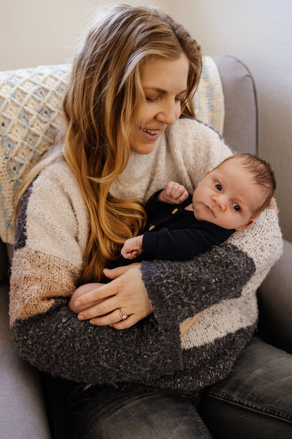 Mom holds her new baby at in-home lifestyle photo session with Cindy Tucey Photography