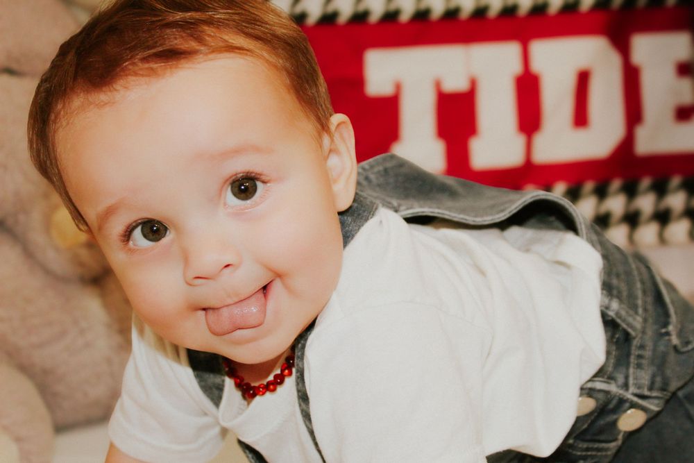 Smiling toddler lying on couch with red and white stripe pattern in background.