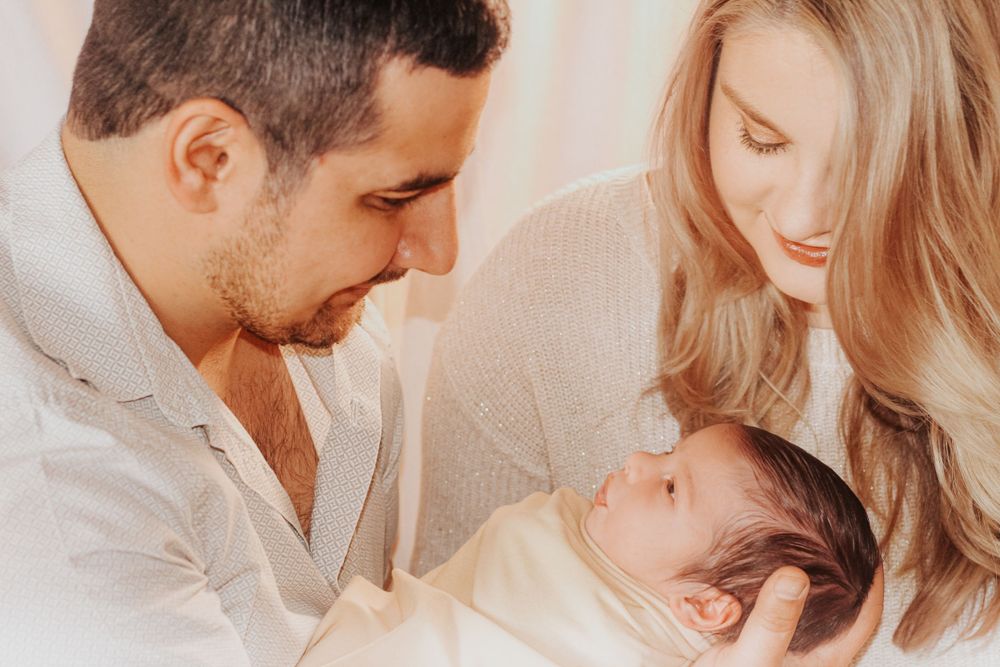 Parents gazing lovingly at their newborn baby in a tender family moment.