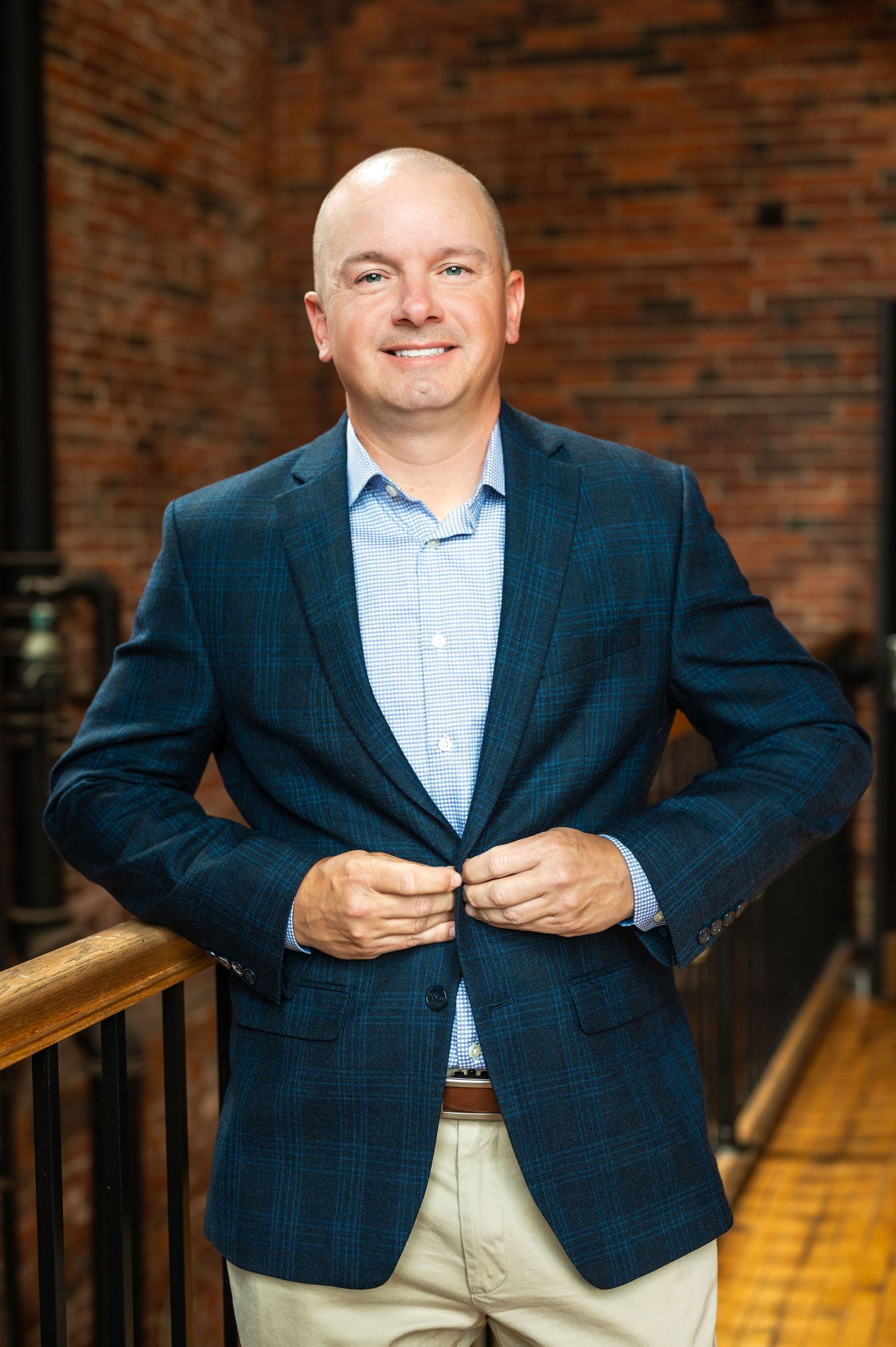 Portrait sitting on wooden steps with exposed brick wall backdrop.