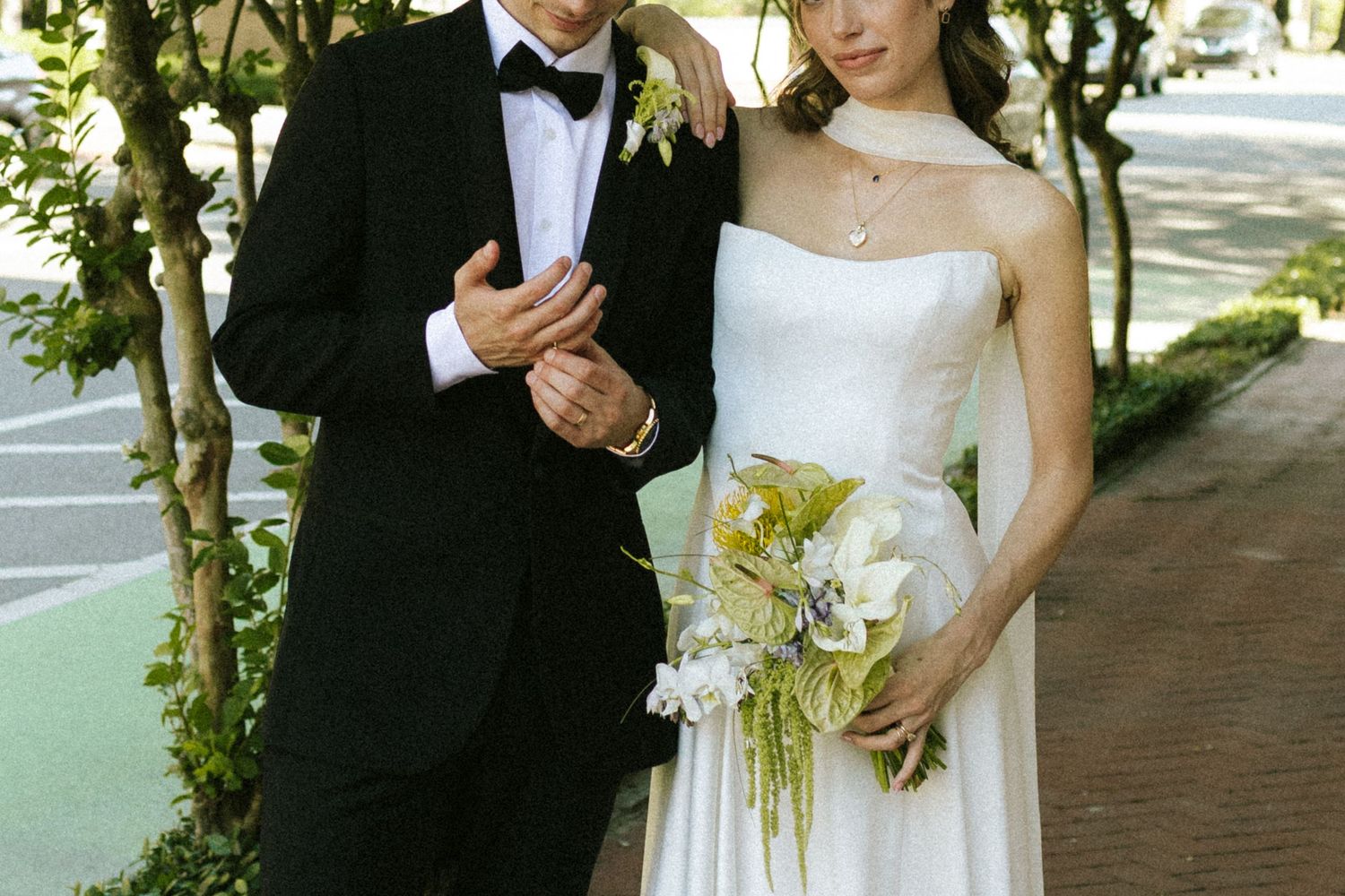 A close up shot of a groom's hands fidgeting with his ring while his bride rests on his shoulder