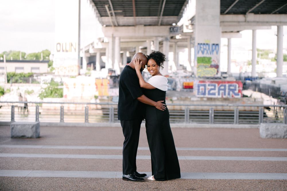 A couple dances intimately beneath an urban overpass as a photographer captures their romantic moment.