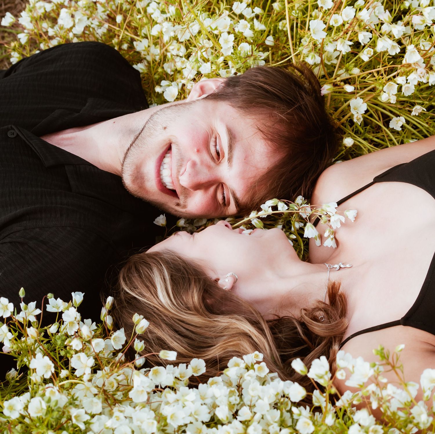 Two lovers staring at one another in a beautiful field of flowers.