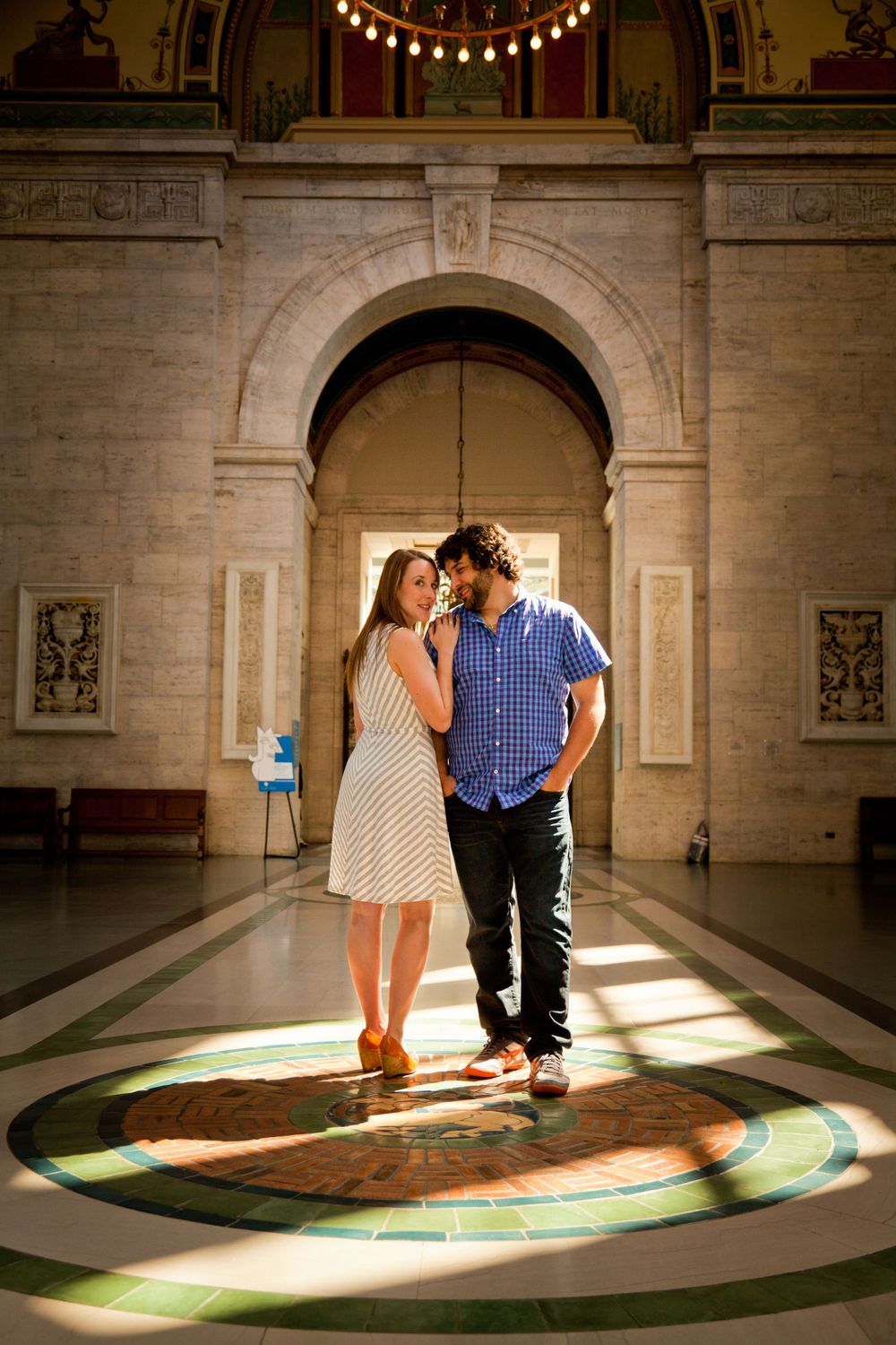 A couple embracing in a grand architectural space with ornate arches and stained glass windows during their engagement session