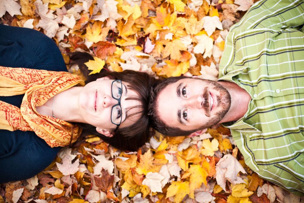 A couple laying in autumn leaves during their engagement session.