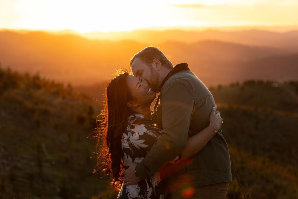 Couple sharing a romantic moment at golden sunset with mountain views in the background.