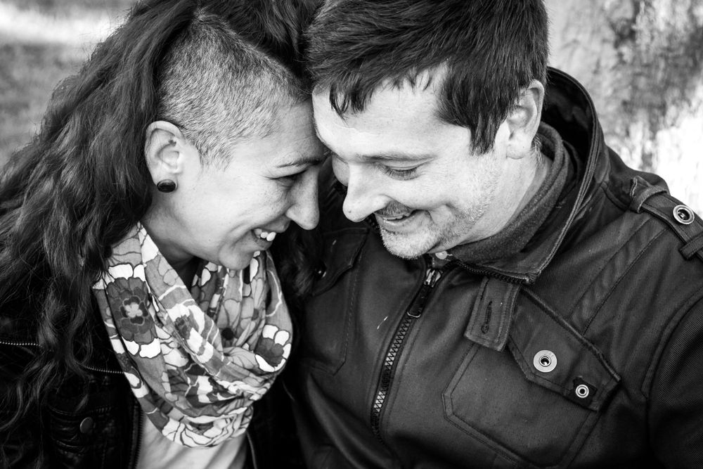 A black and white portrait of a couple sharing an intimate laughing moment.