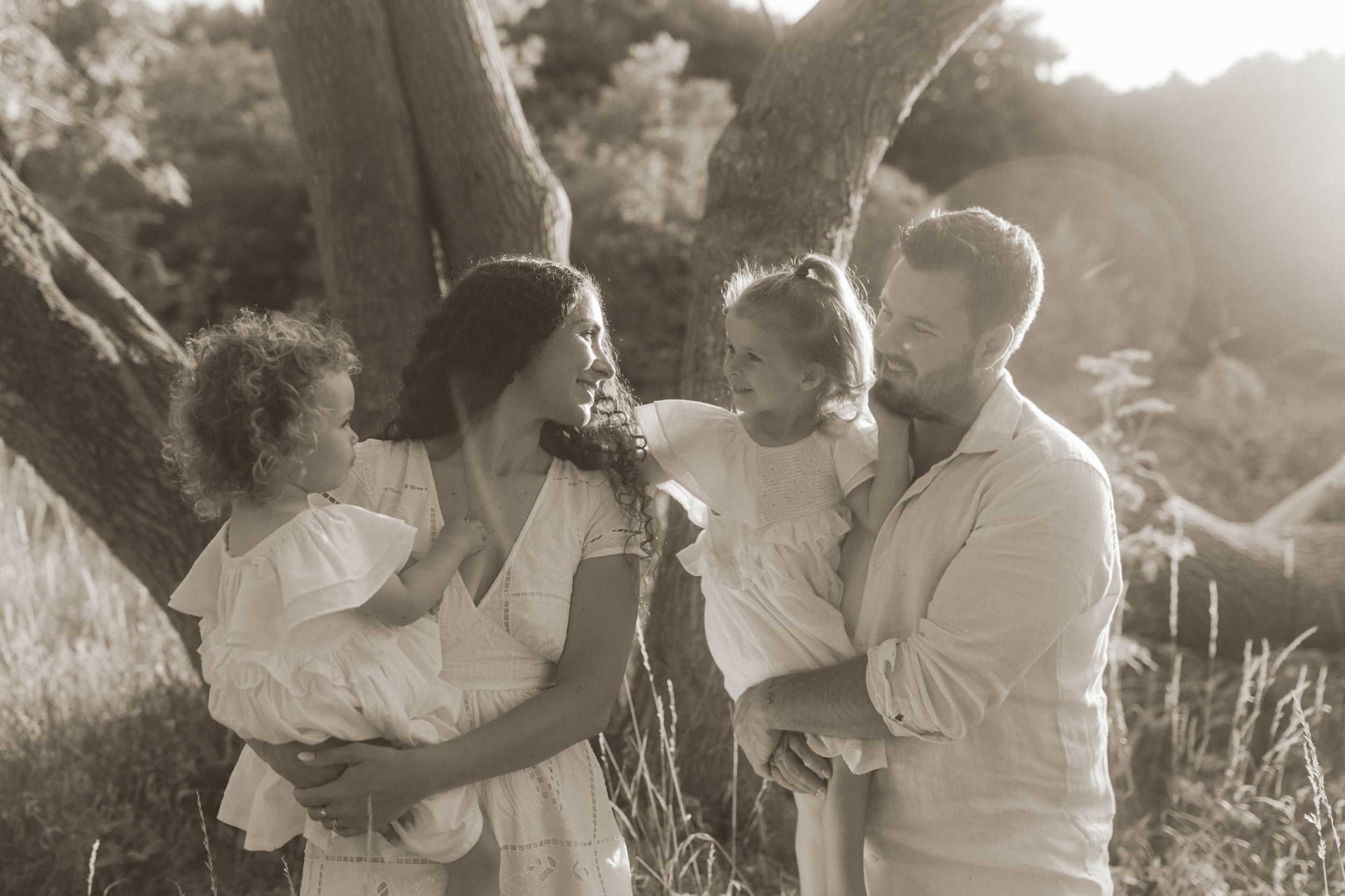 A vintage-style family portrait captured in black and white under a majestic tree.