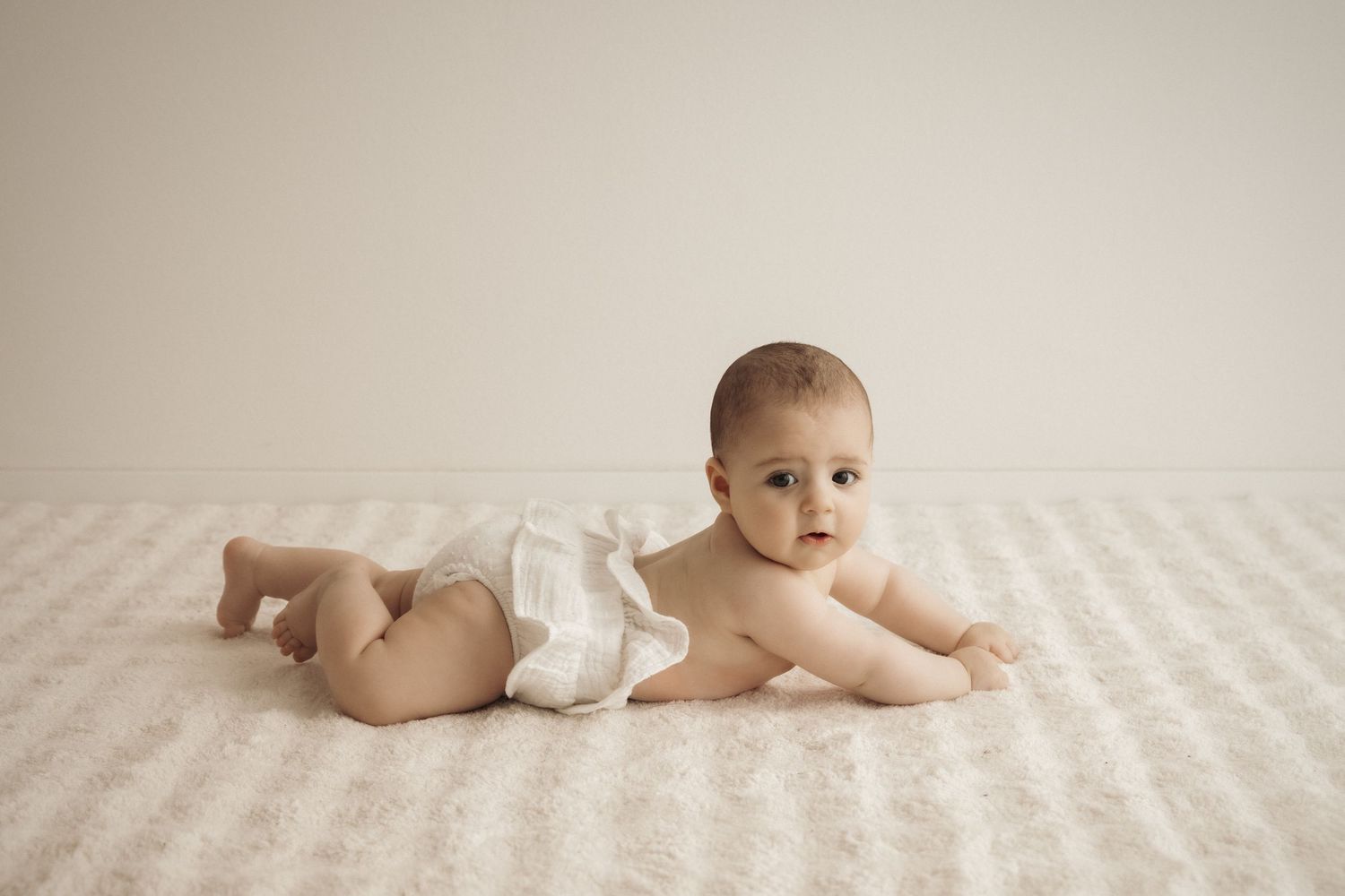 A baby crawls across a soft cream-colored textured blanket in a progressive motion sequence.