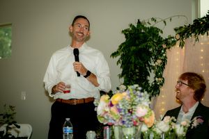 A wedding toast being given during an indoor reception with decorative lighting and plants.