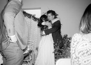 Black and white photo of a wedding ceremony moment with string lights in the background.