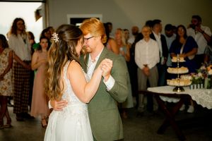A couple shares their first dance at a wedding reception with guests watching nearby.
