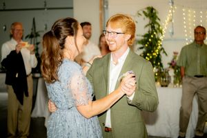 A couple dances together at a wedding reception with twinkle lights in the background.