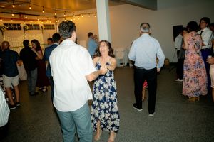 Wedding guests dance and celebrate on a reception dance floor with string lights overhead.