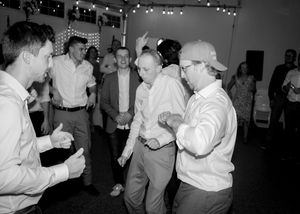 A group dances enthusiastically at a reception in black and white.