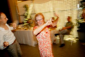 A guest dances energetically at a reception with motion blur and string lights.