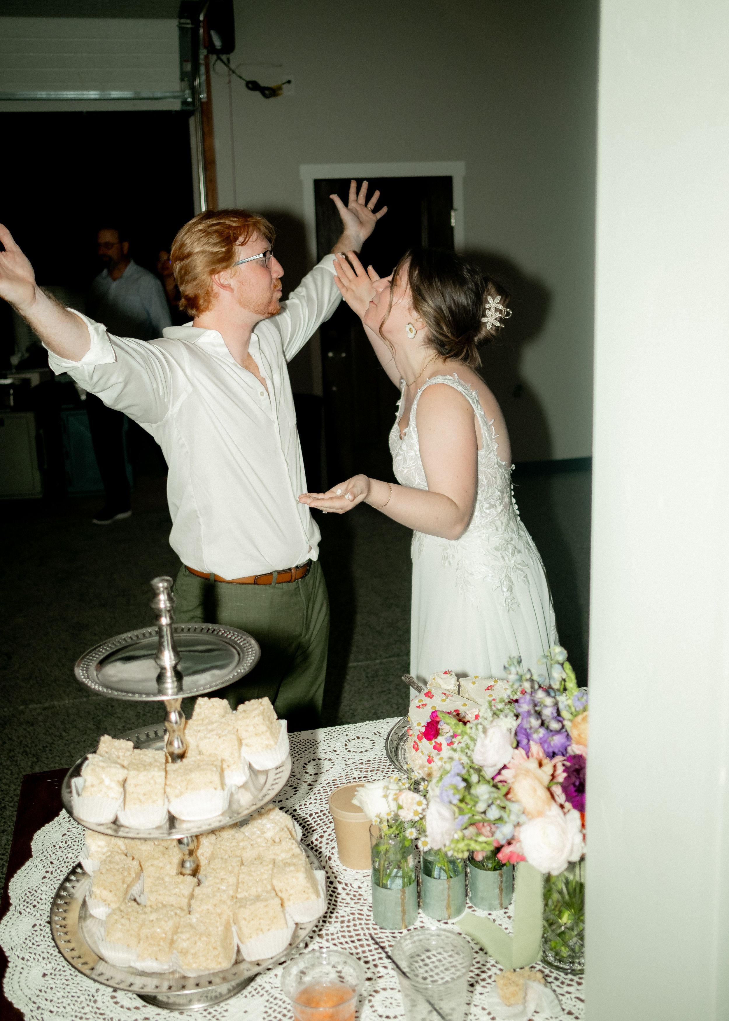 Celebratory moment near a tiered dessert display at a wedding reception.