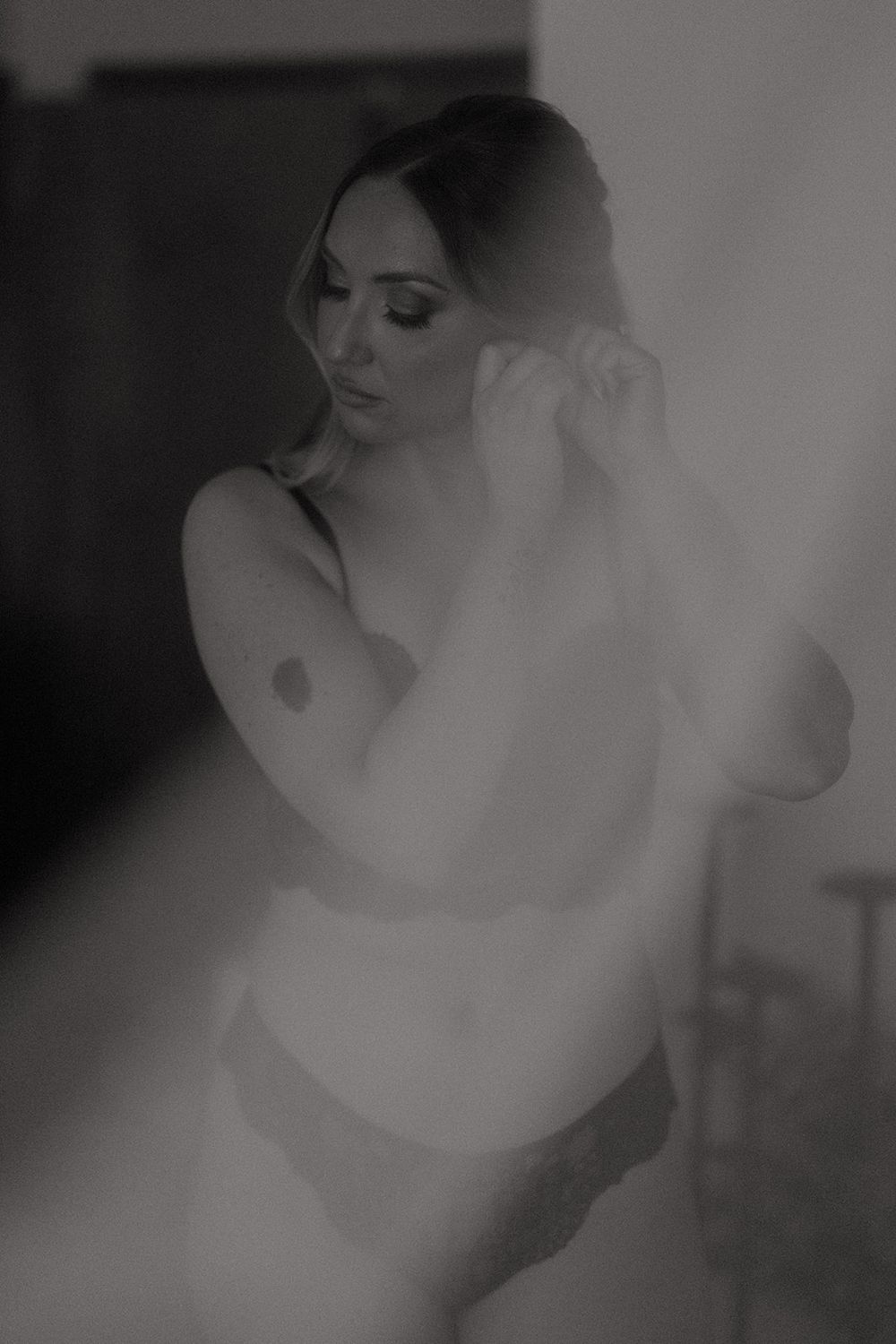 Black and white boudoir photography with soft focus and ethereal lighting creating a dreamy, artistic effect.